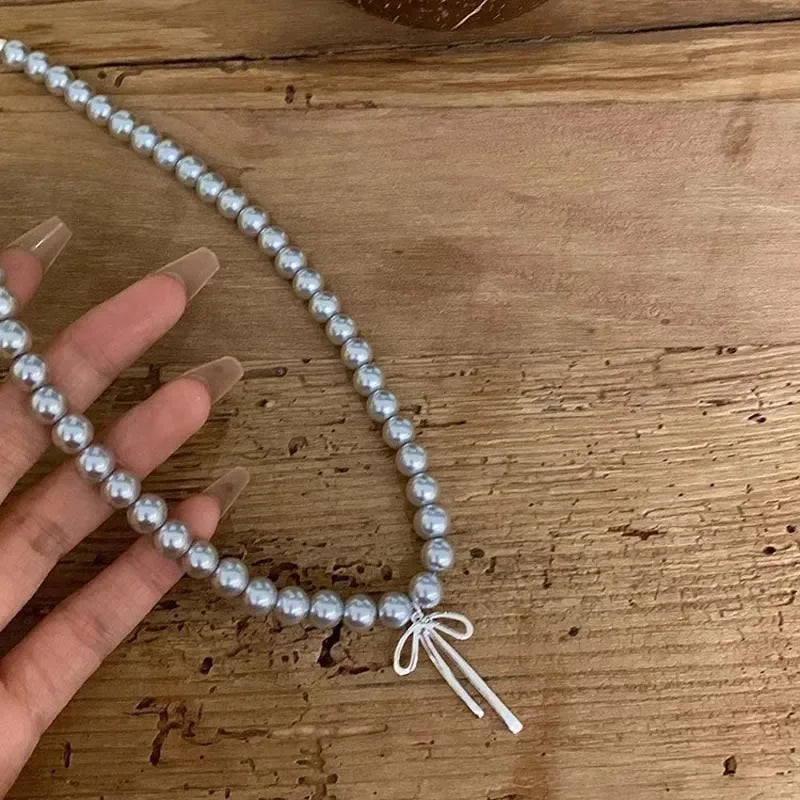 Collier Pendentif avec Perles Grises et Noeud de Papillon